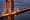 Golden Gate Bridge illuminated at dusk with warm golden lighting on tower and suspension cables